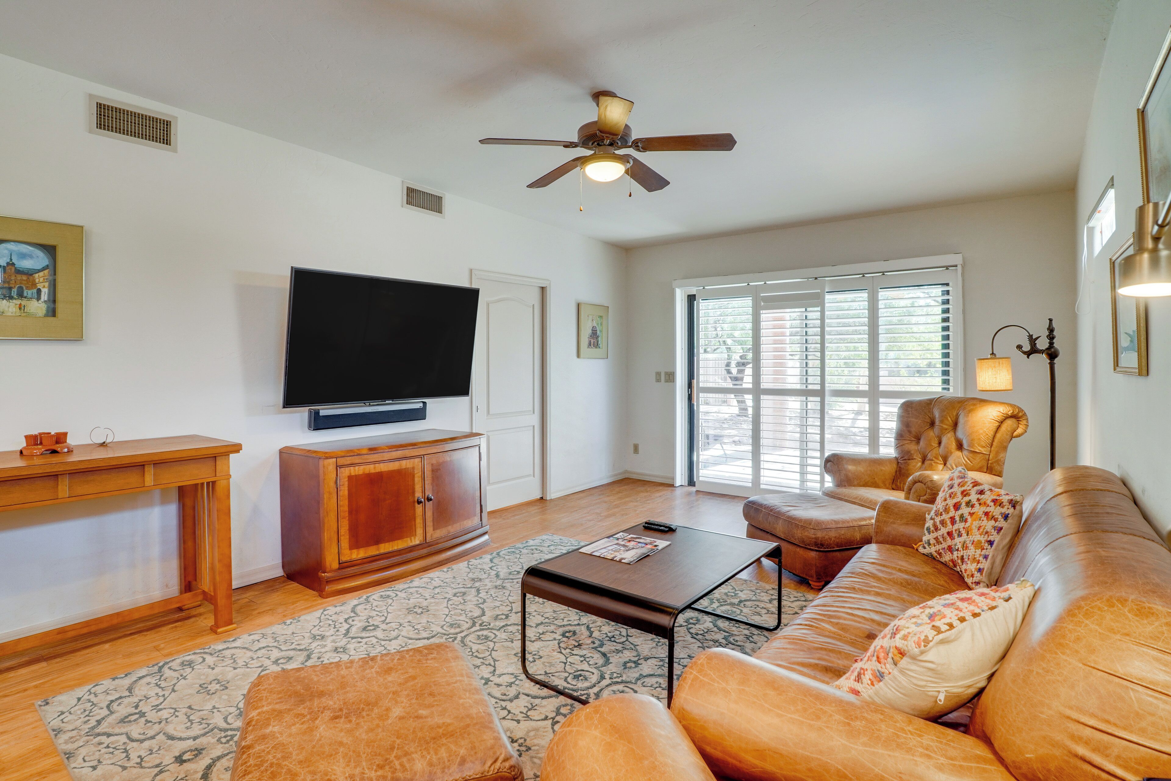 A living room with a television, sofa, armchair, and a ceiling fan.