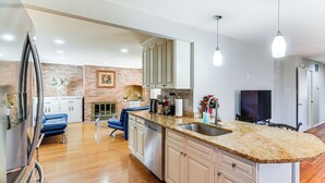 A modern kitchen with granite countertops, stainless steel appliances, and a brick accent wall. - 5 Mi to Lake Accotink Park: Modern Home w/ Yard (Springfield)