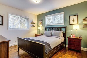 A bedroom with a wooden bed, two bedside tables with lamps, a nightstand, and a window with blinds. - Easy I-25 Access! Vibrant North Denver Home (Denver)