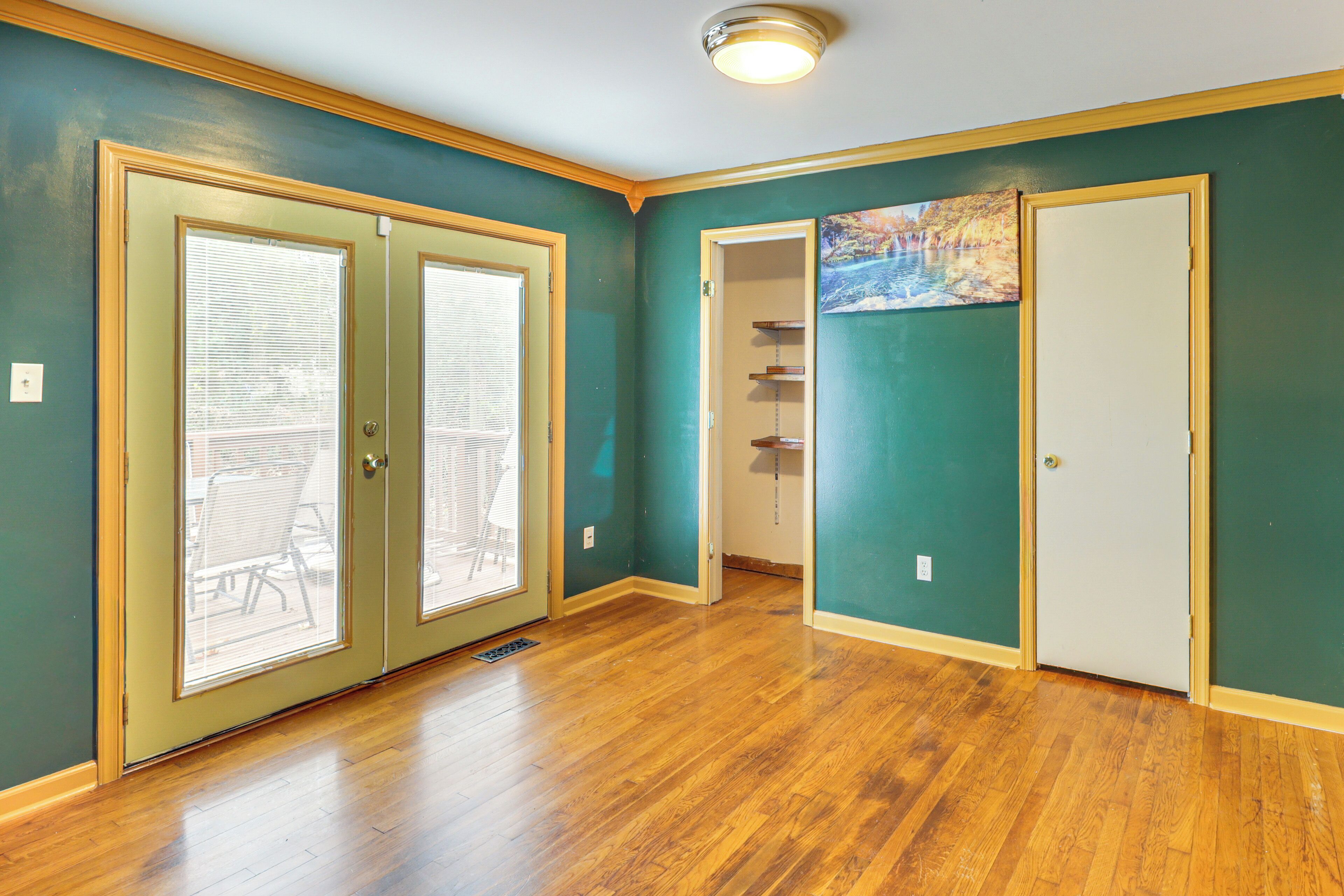 A room with wooden flooring, teal walls, and a door leading to a balcony.