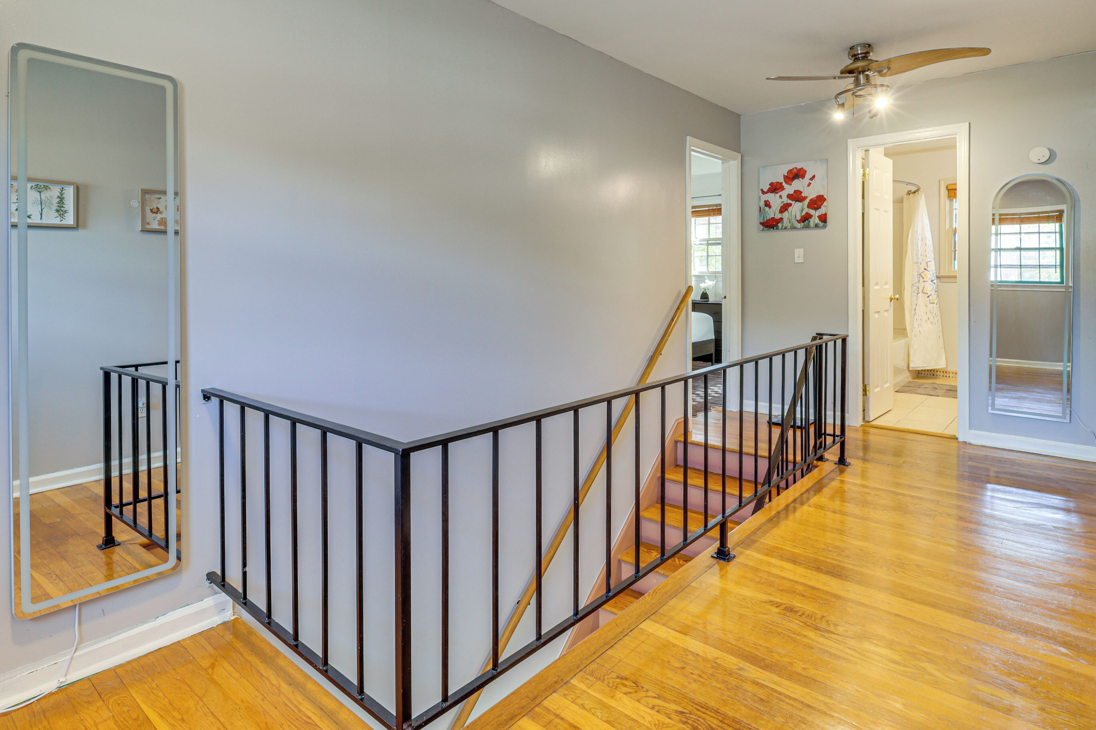 A staircase with a wooden handrail and black metal railing, leading to an upper floor.
