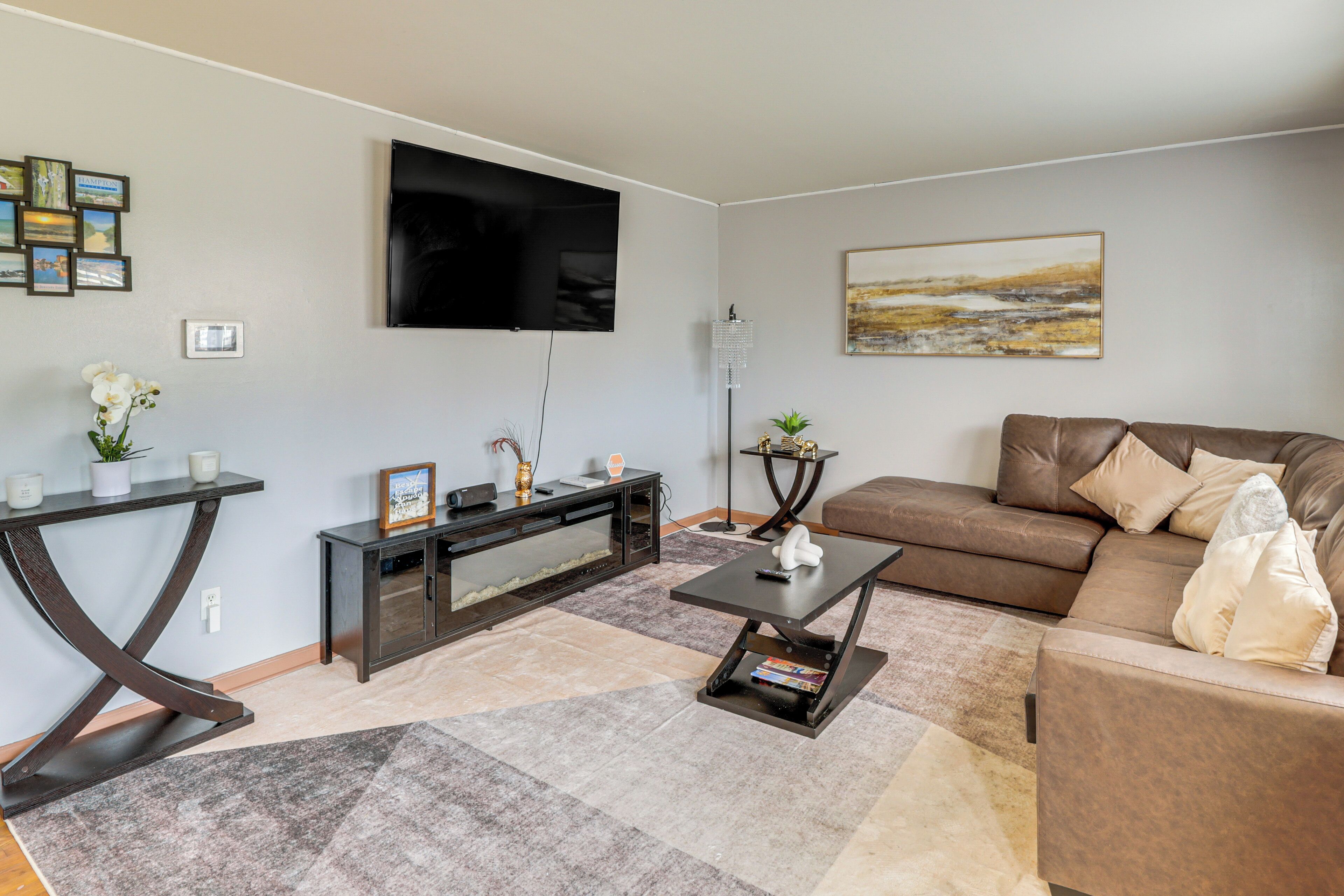 Un salon comprenant un téléviseur à écran plat, un canapé en cuir marron, une table basse, une console et un tapis.