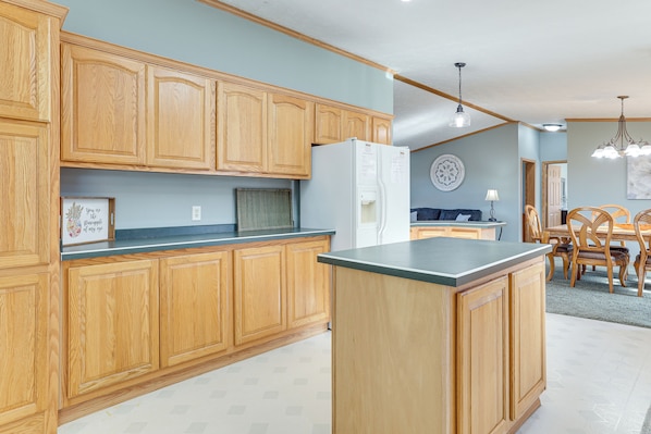 A kitchen with wooden cabinets, a refrigerator, and a dining area with a table and chairs. - 8 Mi to Dtwn Rochester: Peaceful Home w/ Deck! (Rochester)