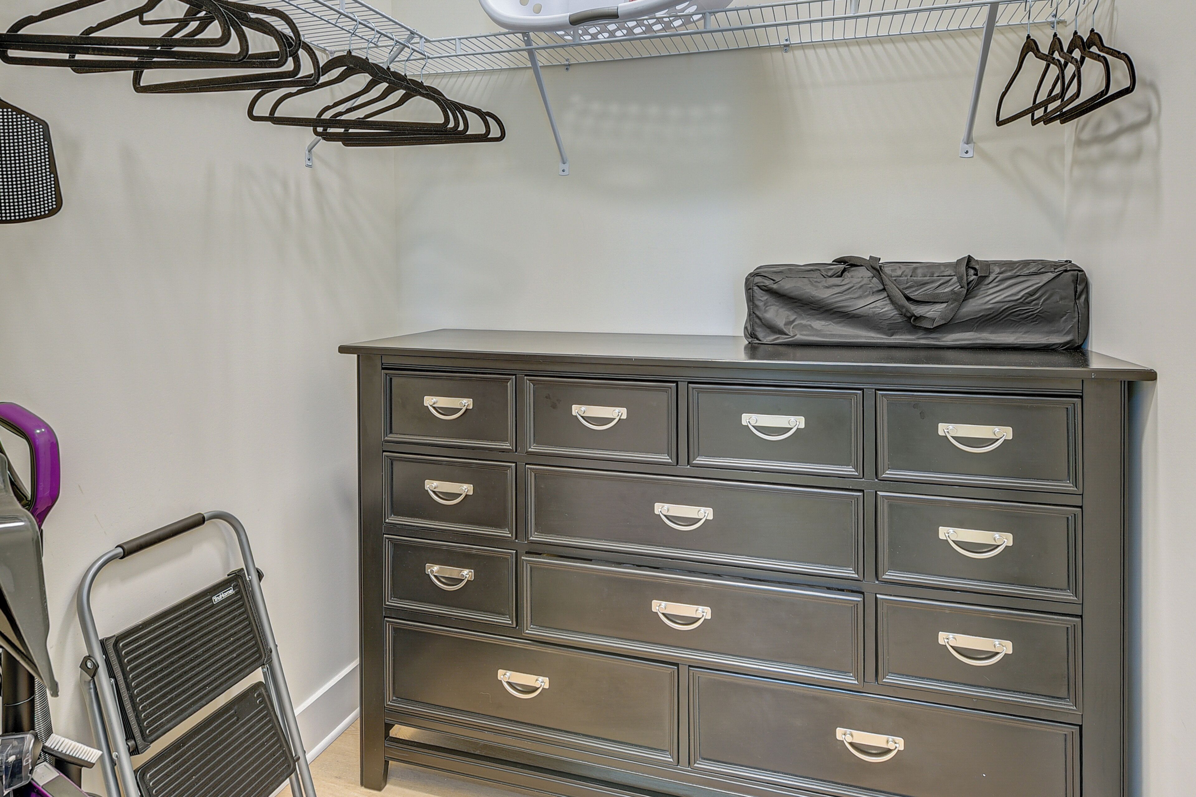A storage unit with multiple drawers and a small bag on top.