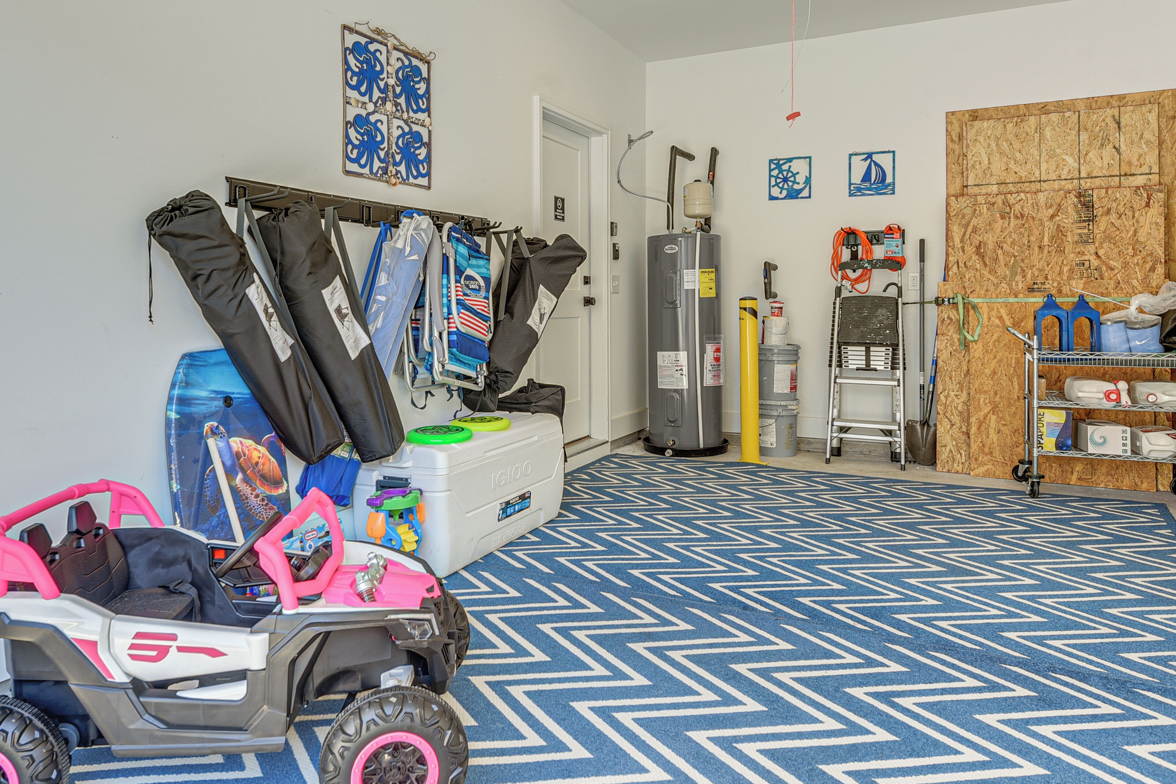 A room with a blue patterned floor, a toy vehicle, a storage unit, and various items on shelves and a rack.