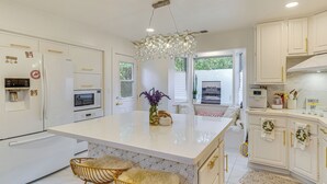 A modern kitchen with white cabinetry, a central island with stools, a microwave, and a refrigerator. - Work & Relax! Updated Walnut Creek Home w/ Office (Walnut Creek)