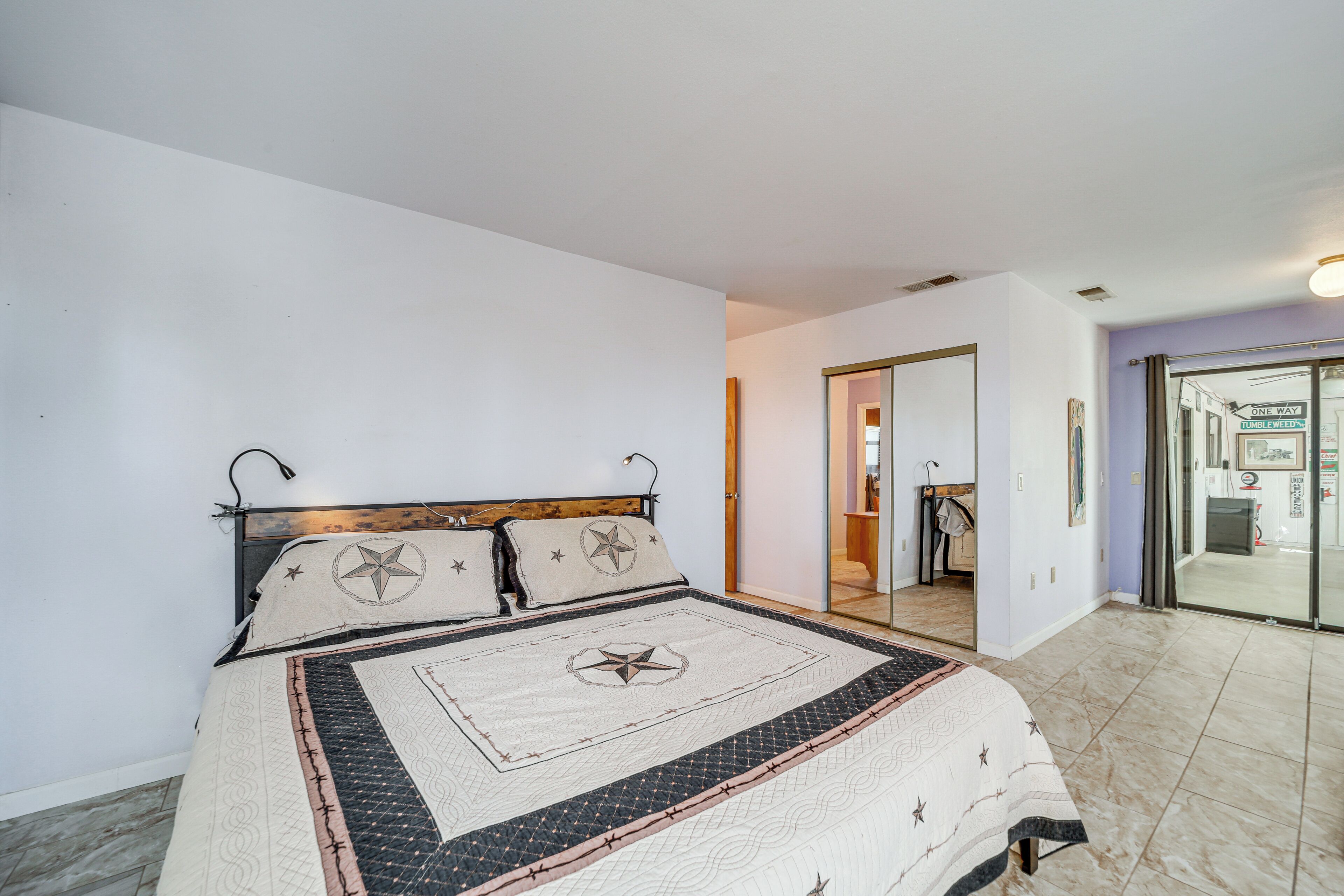 A bedroom with a bed, a door leading to a bathroom, and a view of the outside.