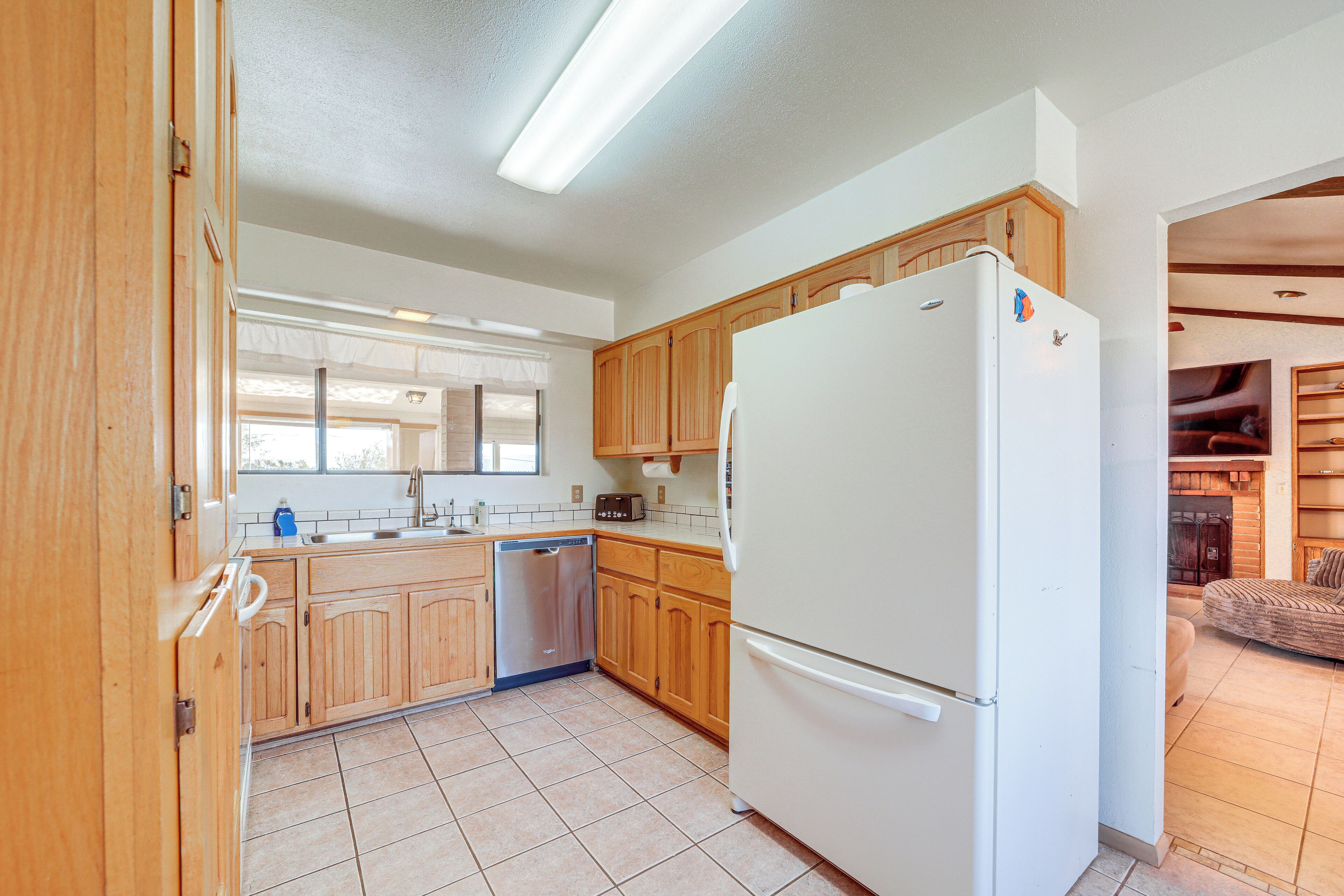 A kitchen with wooden cabinets, a white refrigerator, and a dishwasher.