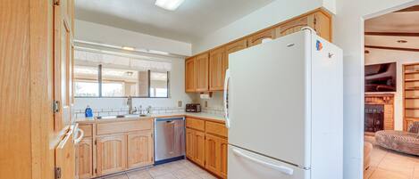 A kitchen with wooden cabinets, a white refrigerator, and a dishwasher.
