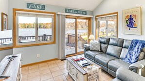 Ein Wohnzimmer mit Seeblick, einer Couch, einem Couchtisch mit Büchern und einem Schild mit der Aufschrift 'LAKE HOUSE'.