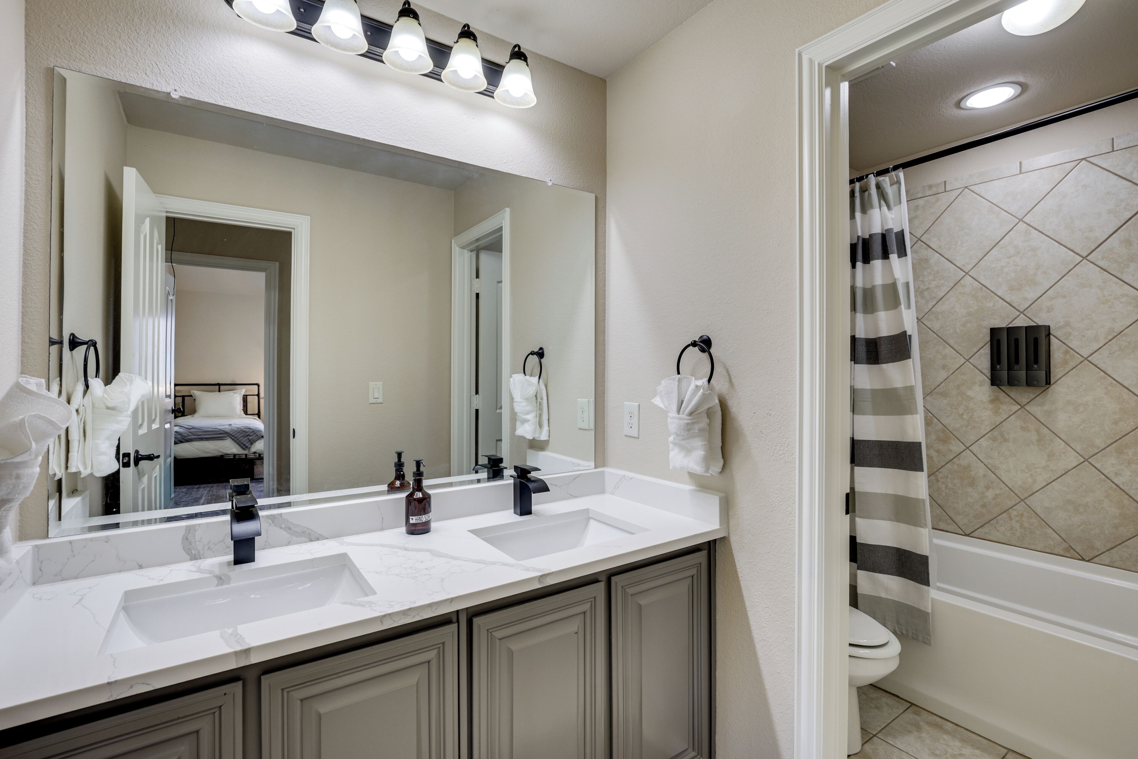 A bathroom with two sinks, a large mirror, and a shower area.