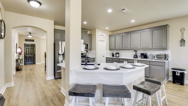 A modern kitchen with a central island, bar stools, and a view into the dining area. - 3,000-sq-ft Family Home in Anna w/ Game Room! (Anna)