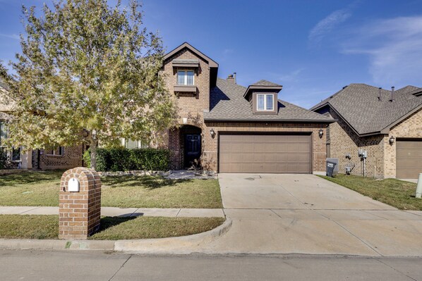 A residential house with a brick facade, a front garage, and a well-maintained lawn.