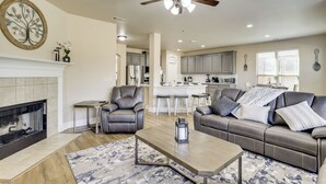A modern living room with a fireplace, leather sofa, and a ceiling fan. - 3,000-sq-ft Family Home in Anna w/ Game Room! (Anna)