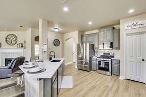 A spacious kitchen with modern appliances, a dining area with a large island, and a cozy seating area with a fireplace.