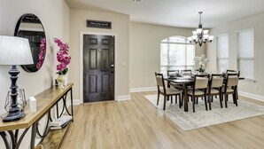 A dining area with a wooden table, chairs, a chandelier, and a mirror on the wall. - 3,000-sq-ft Family Home in Anna w/ Game Room! (Anna)