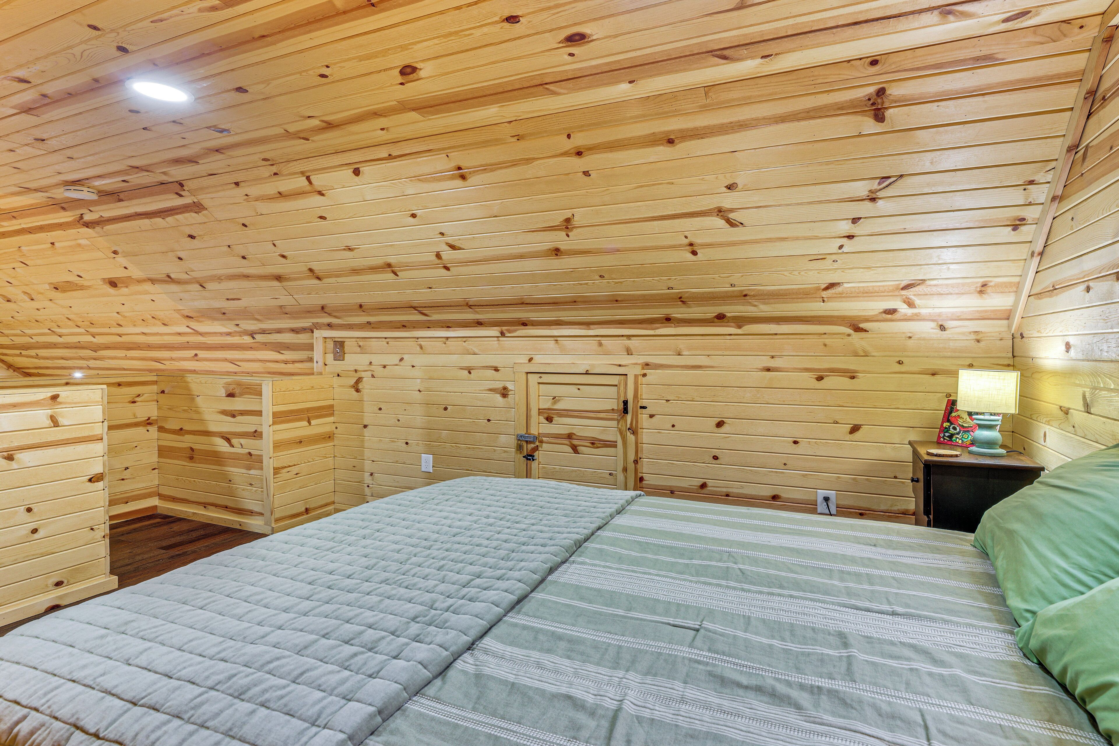 Um quarto com painéis de madeira, uma cama, uma mesa de cabeceira e uma porta.