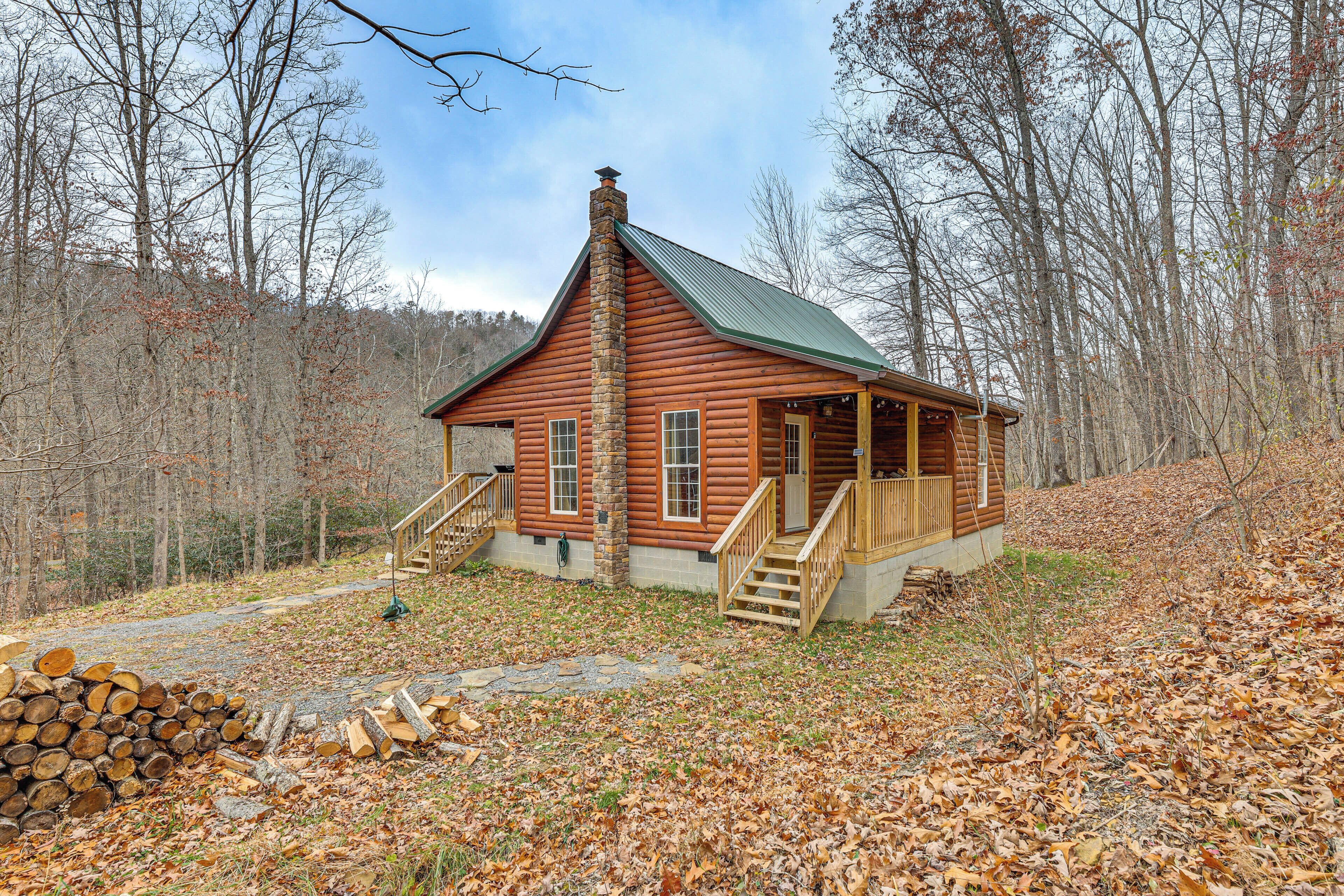 A log cabin with a stone chimney, wooden steps, and a porch.