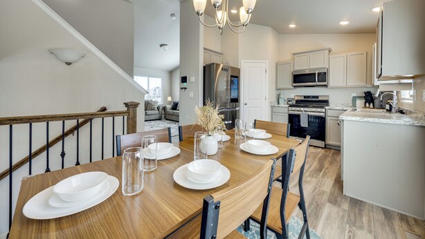 A dining area with a wooden table set for four, a chandelier, and a view into the kitchen. - 'mountain Family Getaway' in Colorado Springs! (Colorado Springs)