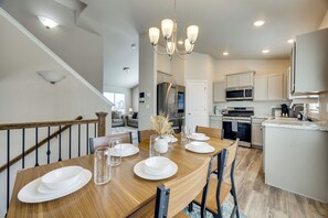 A dining area with a wooden table set for four, a chandelier, and a view into the kitchen. - 'mountain Family Getaway' in Colorado Springs! (Colorado Springs)