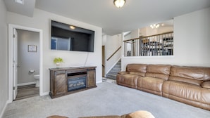 A living room with a brown leather sofa, a wooden entertainment center, and a staircase leading to a dining area. - 'mountain Family Getaway' in Colorado Springs! (Colorado Springs)