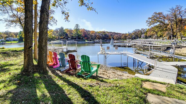 A lakeside view with colorful Adirondack chairs, a dock, and a bridge. - Private Beach! Lakefront Cabin in Panora (Panora)