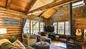 A log cabin interior with a fireplace, comfortable seating, and a television. - Private Beach! Lakefront Cabin in Panora (Panora)