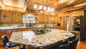 A spacious kitchen with wooden cabinets, a granite countertop, and modern appliances. - Private Beach! Lakefront Cabin in Panora (Panora)