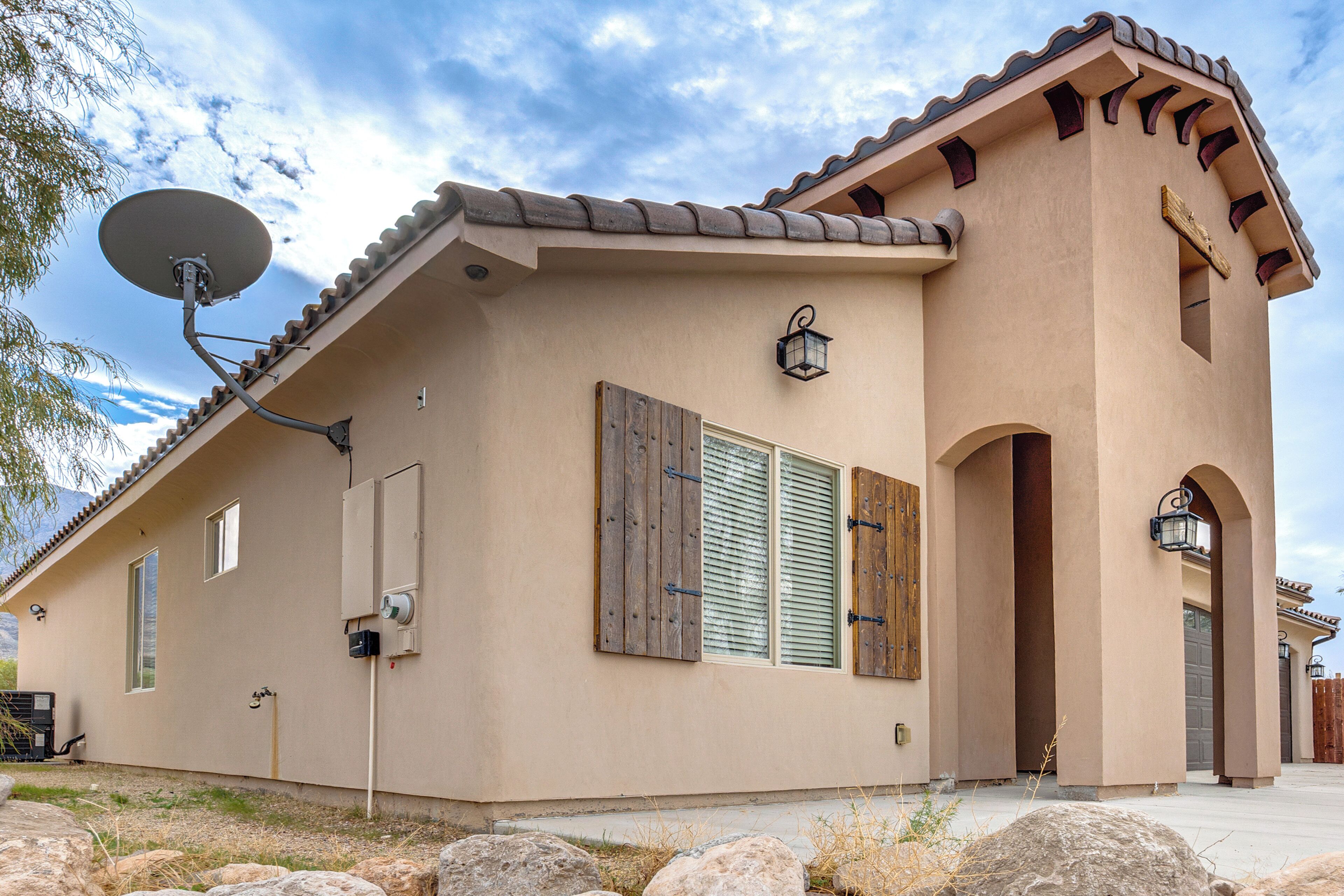 A single-story house with a satellite dish, wooden shutters, and a stone facade.