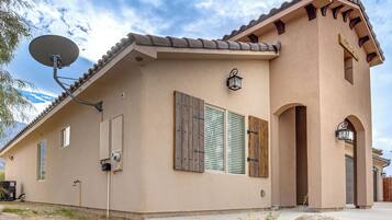 A single-story house with a satellite dish, wooden shutters, and a stone facade.