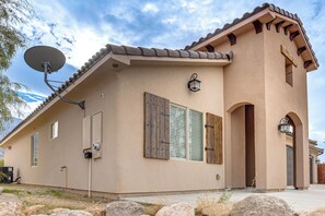 Una casa de planta baixa amb antena parabòlica, persianes de fusta i façana de pedra.
