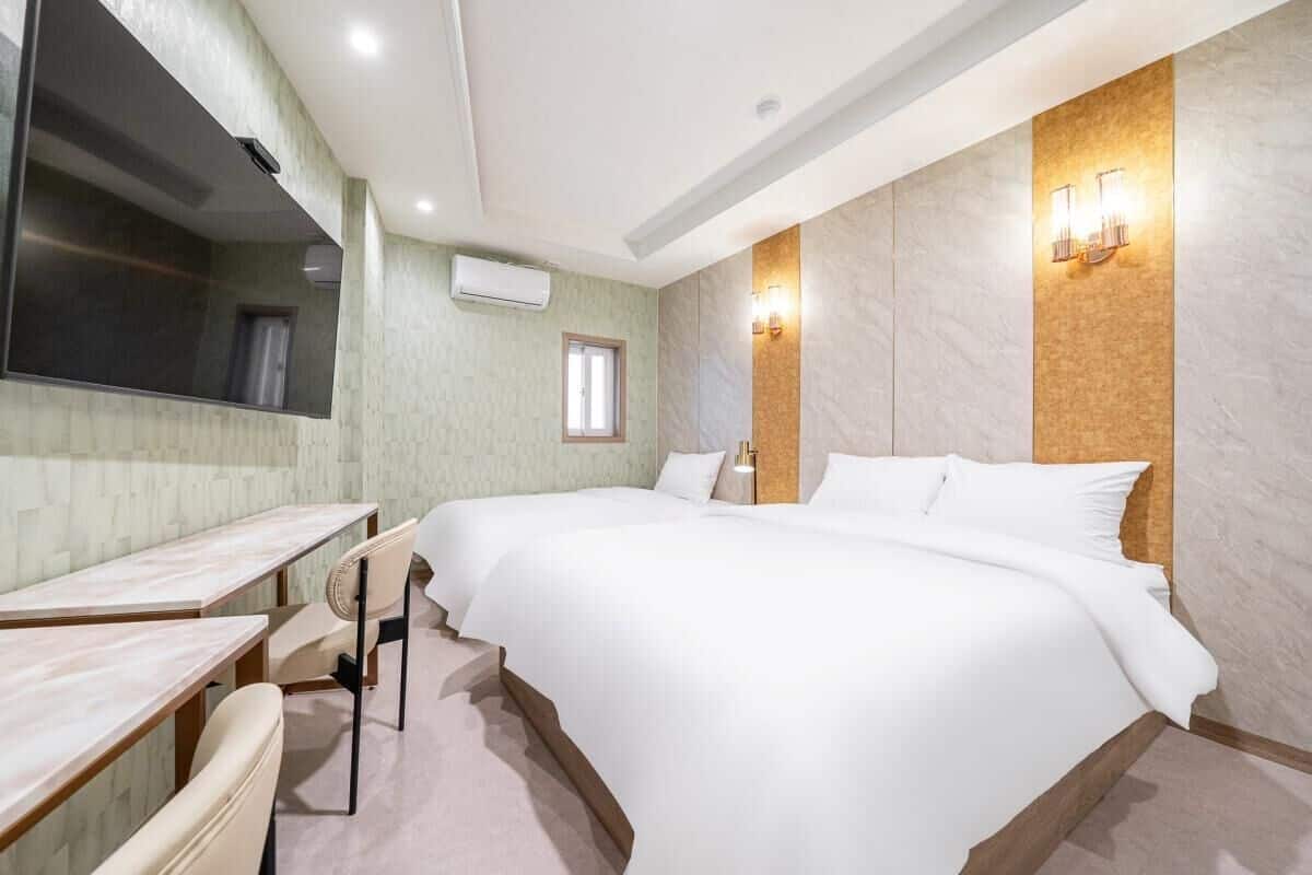 Habitación de hotel con una cama grande, un escritorio, una silla, un televisor de pantalla plana y un aire acondicionado de pared.