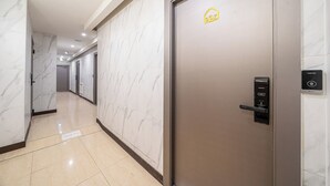 A hallway with marble walls and a modern door with a lock and card reader. - The Stay (Seoul)