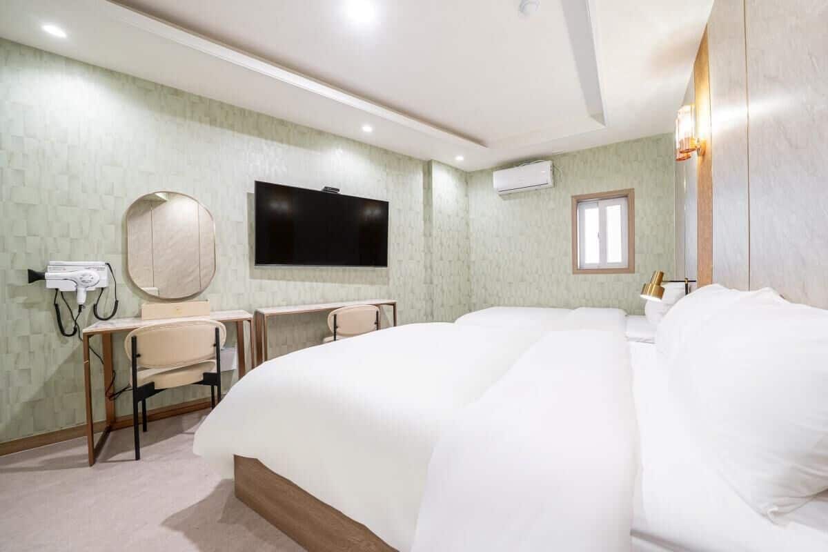 Habitación de hotel con una cama grande, un escritorio con silla, un televisor y un espejo.