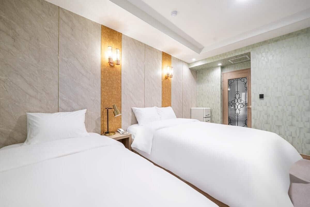 Ein Hotelzimmer mit zwei Betten, einem Nachttisch, einem Telefon und Wandleuchten.
