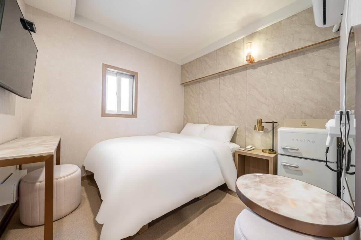 Ein modernes Hotelzimmer mit Bett, Nachttisch und integriertem Föhn.