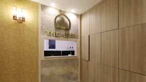 A hotel room with a wooden wardrobe, a vanity with a mirror, and a wall-mounted light fixture. - The Stay (Seoul)