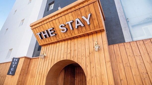 A hotel entrance with a wooden sign reading "THE STAY" and a smaller sign below stating "HOTEL". - The Stay (Seoul)