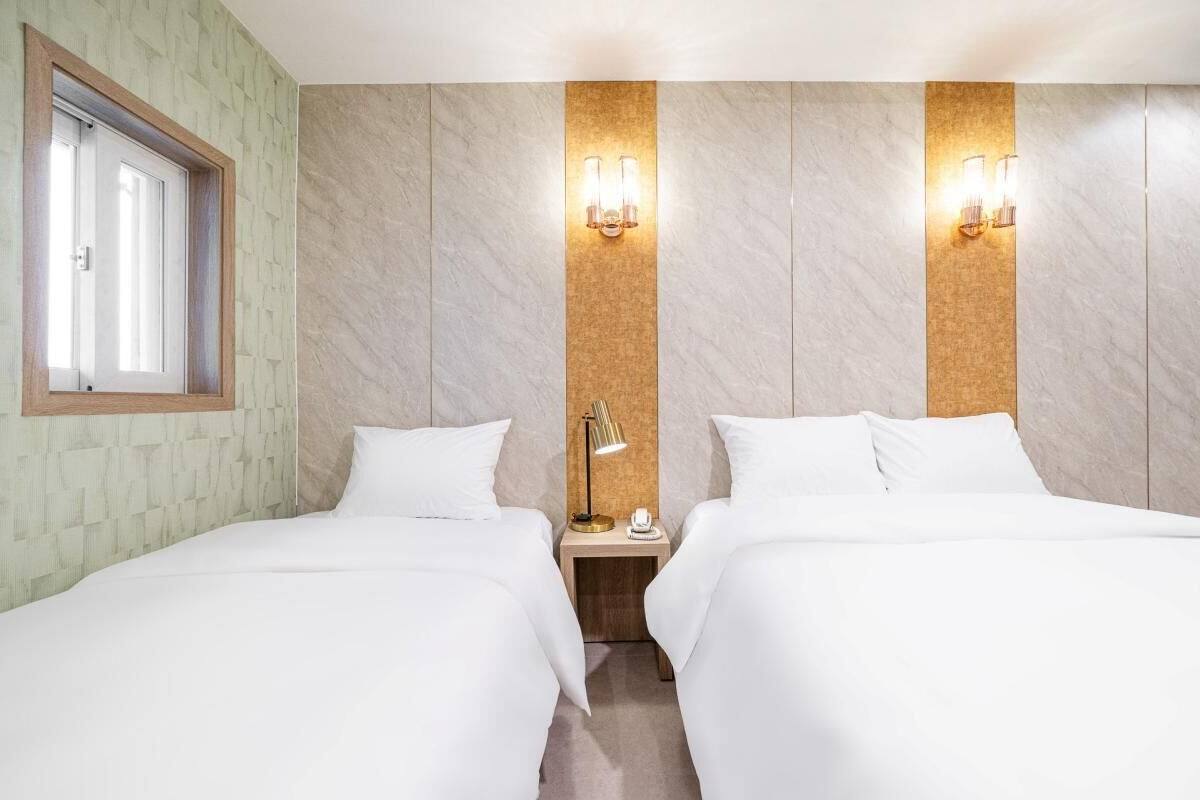 Ein Hotelzimmer mit zwei Betten, einem Fenster und Wandleuchten.