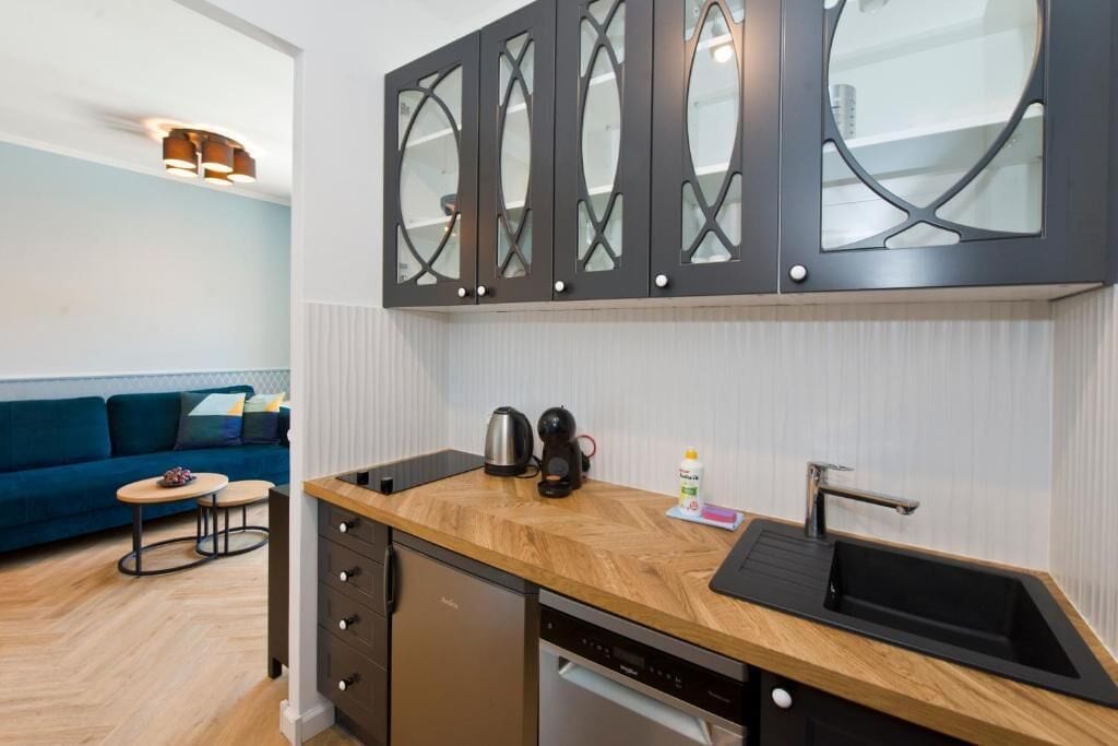 A compact kitchen with a wooden countertop, a built-in dishwasher, and a black sink.