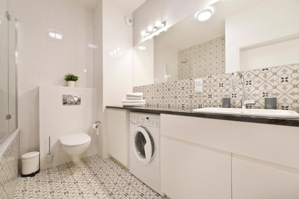 A modern bathroom with a toilet, washing machine, and sink.