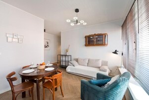 Ein modernes Wohnzimmer mit Essbereich, Sofa und blauem Sessel.