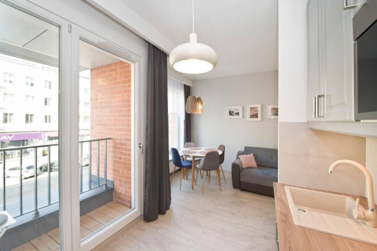 En modern lägenhet med balkong, matplats, soffa och kök.