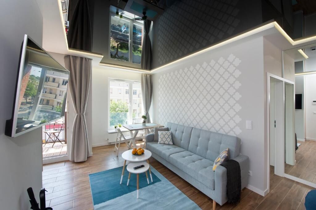 A modern living room with a grey sofa, a round coffee table, and a TV mounted on the wall.