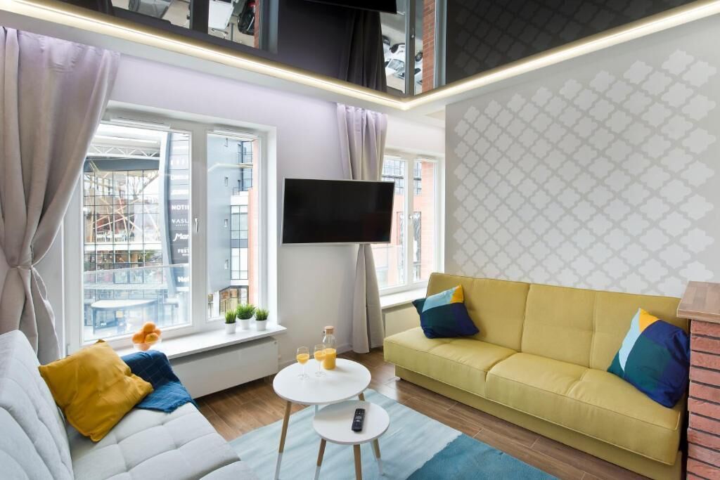 A modern living room with a sofa, a coffee table, and a TV mounted on the wall.