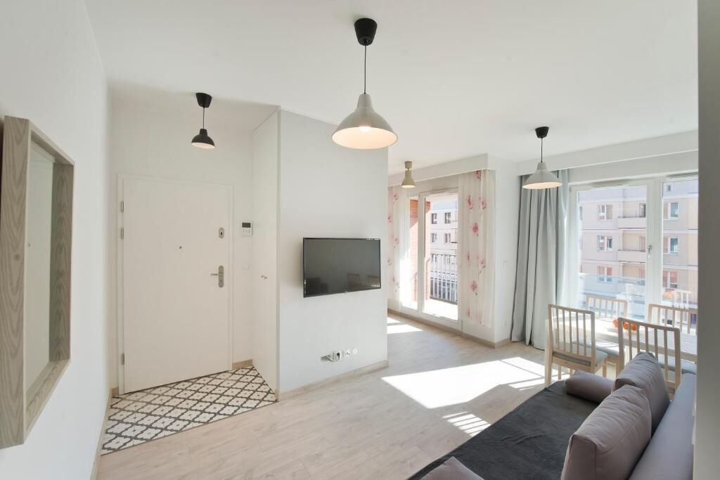 Ein modernes Wohnzimmer mit einer Couch, einem an der Wand montierten Fernseher und einem Balkon mit Geländer.
