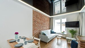 Un soggiorno moderno con zona pranzo, divano, televisore e parete in mattoni.
