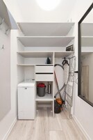 Ein kleiner, übersichtlicher Hauswirtschaftsraum mit Waschmaschine, Wäscheständer und Staubsauger.