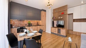 Una cucina moderna con mobili scuri, una parete rivestita in mattoni e un tavolo da pranzo in legno con sedie nere.