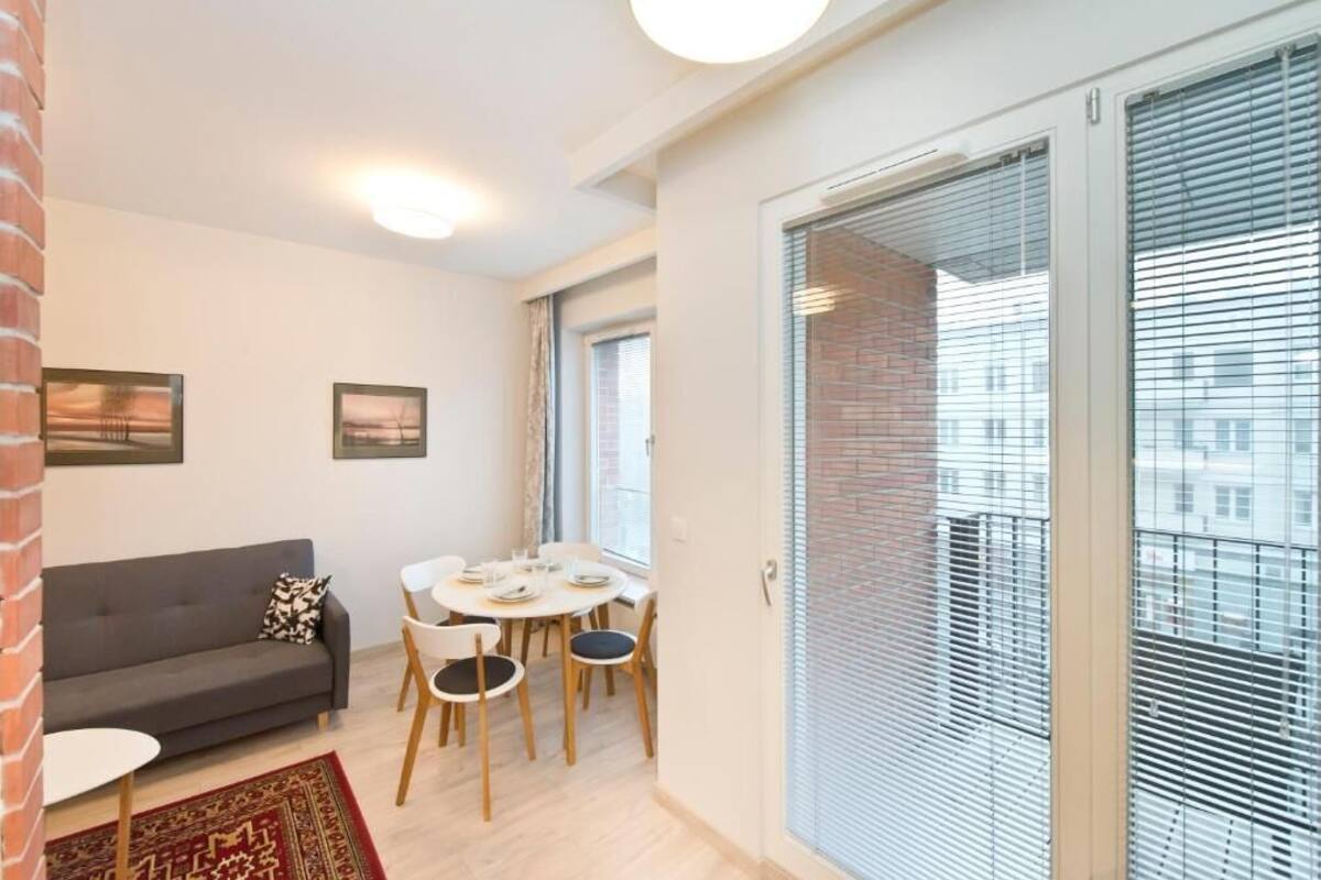 Ett kompakt vardagsrum med en soffa, ett matbord, stolar och en liten matta.